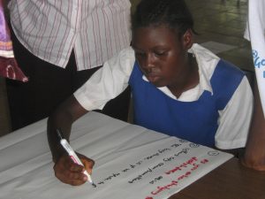 An adolescent girl in Sierra Leone makes a poster in which she is expressing her rights