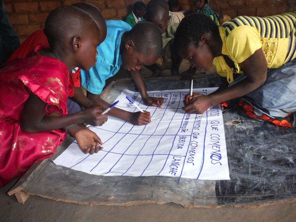 Children writing a poster as part of the PCAAN programme
