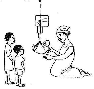 A woman weighs a baby in a sling while two other children look on.