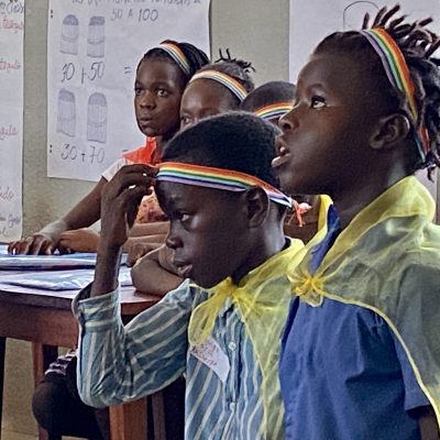 Children in a classroom receive rainbow ribbons to show how they've learned health messages